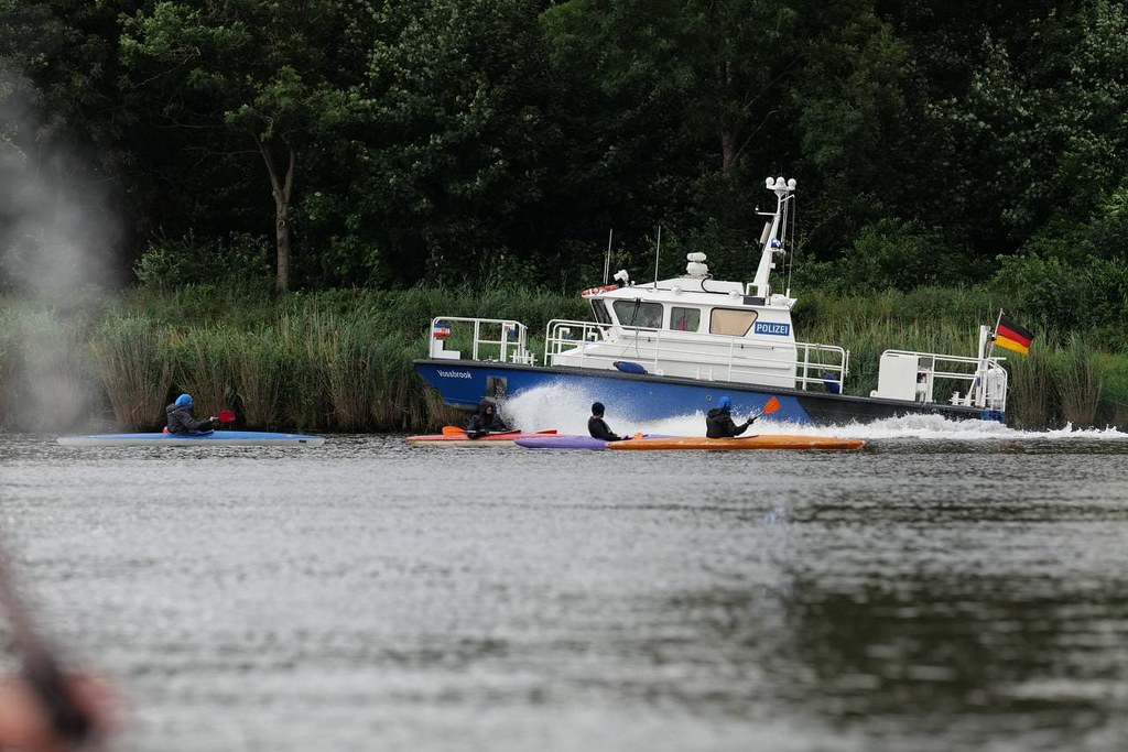 Polizeiboot hinter Kajaks auf dem Wasser