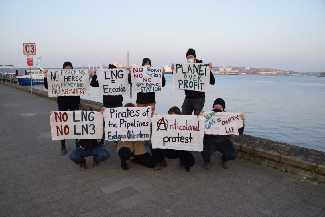 Menschen mit verschiedenen Plakaten gegen LNG vor der Kieler Förde beim Landtag, u.a. "No LNG", "Pirates of the Pipelines - Erdgas (k)entern"